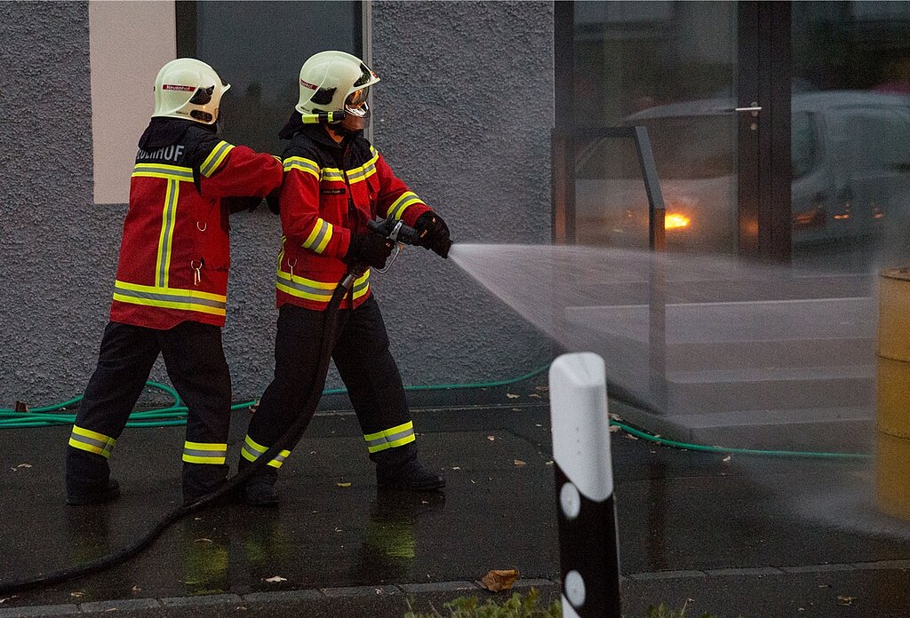 Zwei Feuerwehrleute <em>löschen das Ölfass. </em>
