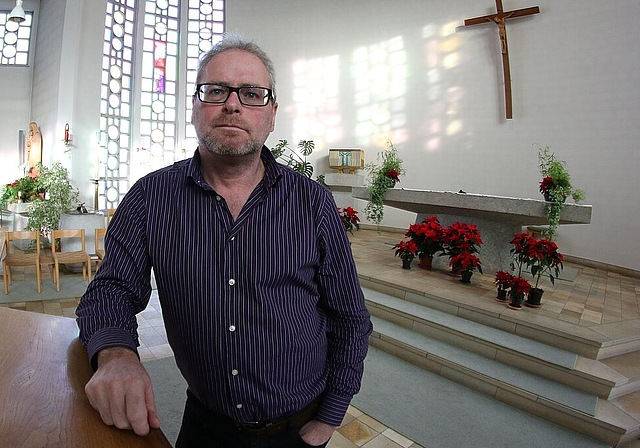 Seelsorger Peter Zürn in der katholischen Kirche vor den Fensterschreiben mit den Visionen von Bruder Klaus. Foto: bär