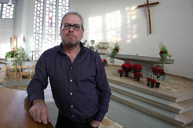 Seelsorger Peter Zürn in der katholischen Kirche vor den Fensterschreiben mit den Visionen von Bruder Klaus. Foto: bär