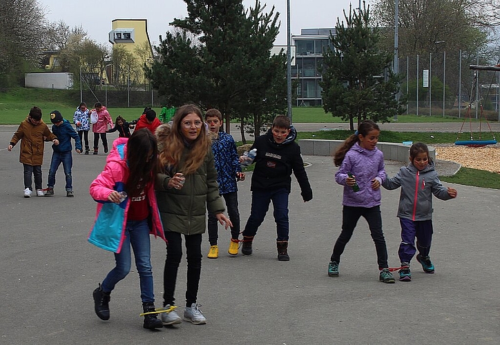Spielerisch Abfall <em>suchen: Mit zusammengebundenen Beinen bringen die Schüler den gefundenen Müll zur Sammelstelle.</em>