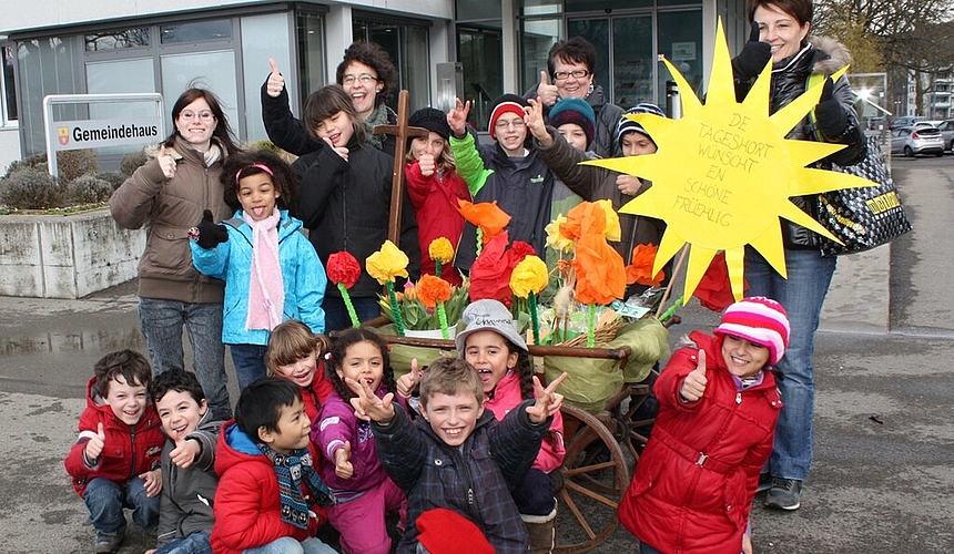 Mit Leiterwagen und Blumen ziehen Hortkinder und -leiterinnen durchs Dorf.
