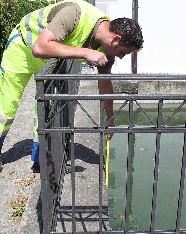 Roger Neuenschwander misst den Abstand vom Wasserspiegel zum Beckenrand. Die Signalkleidung trägt er aufgrund seines Jobs im Rettungswesen. Foto: bär