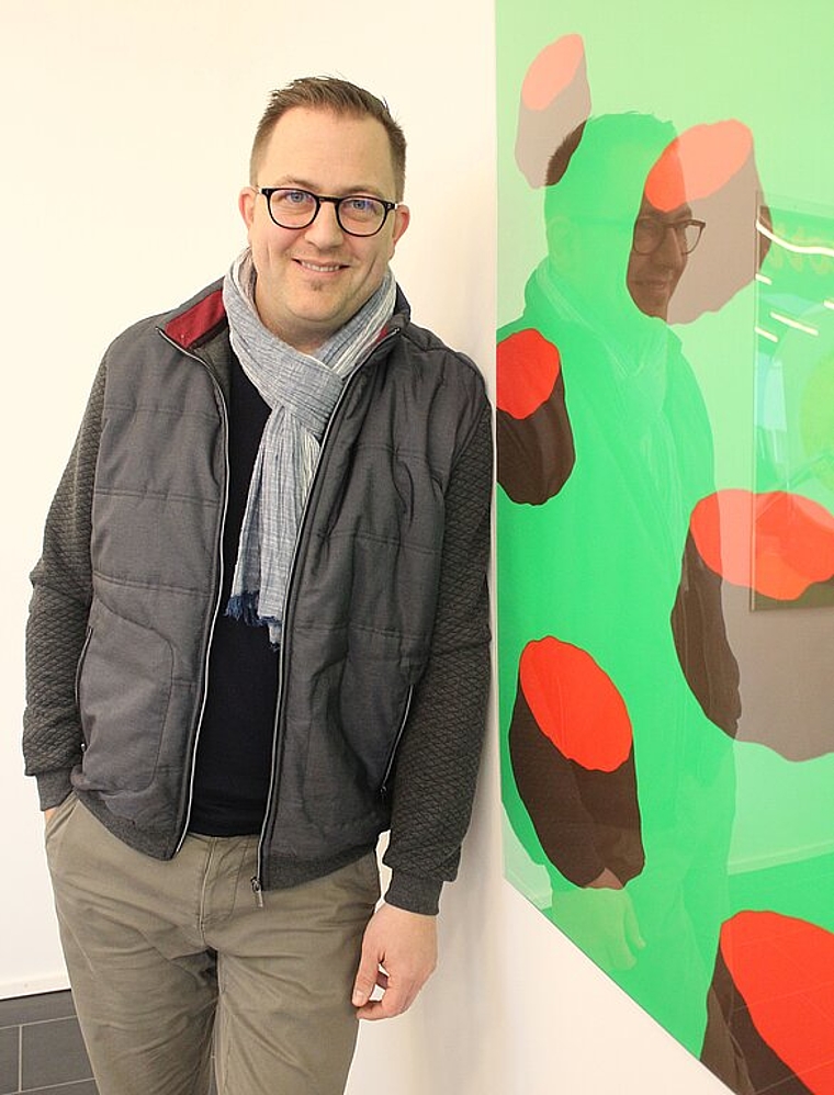 Marc Philip Seidel <em>vor einem Plakat der Ausstellung «Freidimensional». </em><em>rb</em>