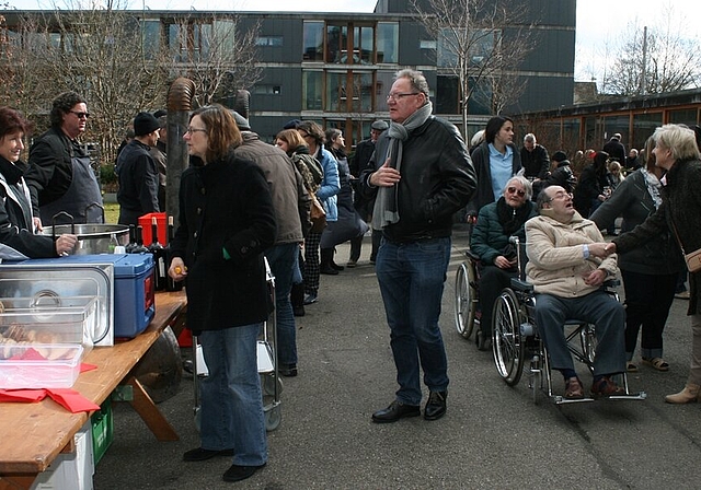 Bewohner und Besucher treffen sich am Suppentag. Politiker wie Gemeinde- und Grossrätin Antoinette Eckert (l.) helfen mit.Gemeinderat Roland Kuster erklärt die Gamellen-Handhabung.Gewusst wie! Suppentransport auf dem Rollator. Fotos: skaSonderwüns