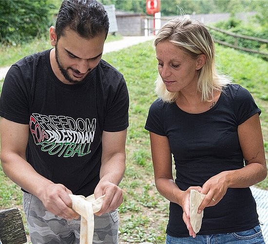 Khaled Deeb zeigt Daniela Aysen<em> wie ein Fladenbrot korrekt geöffnet wird.</em>
