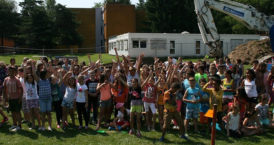 Im Anschluss an die offiziellen Ansprachen durften sechs Kinder vom Schulhausrat, mit Helmen und Neonwesten ausgerüstet, sowie Schulleiterin Bettina Stade mit ihrem pinken Helm auf dem Bagger Platz nehmen,
