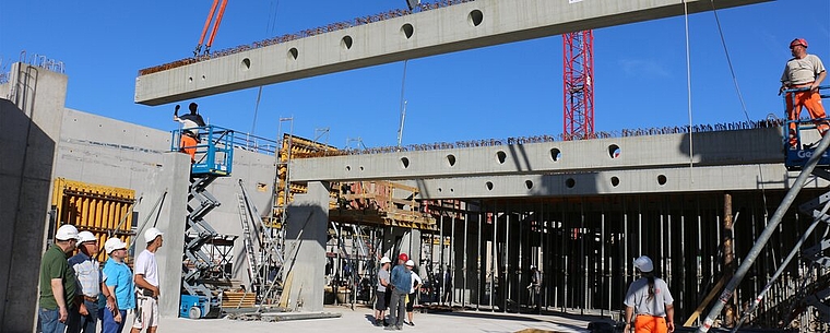 Bauherr und Baufirma schauen zu, wie die Betonträger montiert werden. bär 