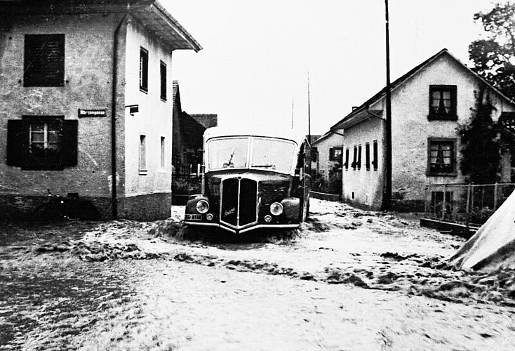 Bus auf der überschwemmten Dorfstrasse. Am Mittwoch, 13. Juli 1955, ging über Wettingen das Gewitter des Jahrhunderts nieder. Ernst Gysi, Küttigen