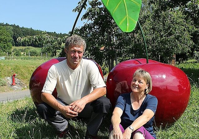 Felix und Brigitte Markwalder aus Würenlos vor den Schaumstoff-Kirschen, die vor ihrem Hof stehen. Rahel Bühler