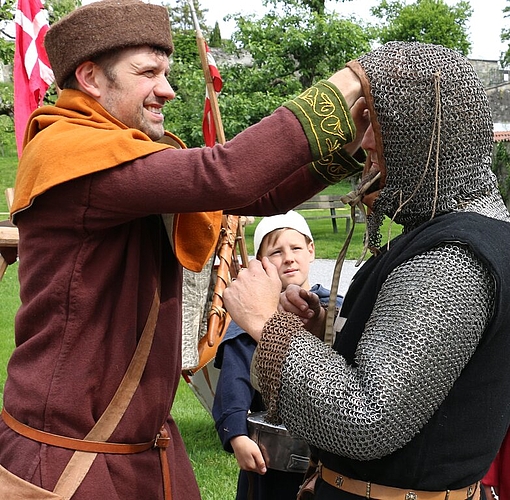 Daniel Severin hilft Timo Hennecke beim Anziehen des Kettenhemds.
