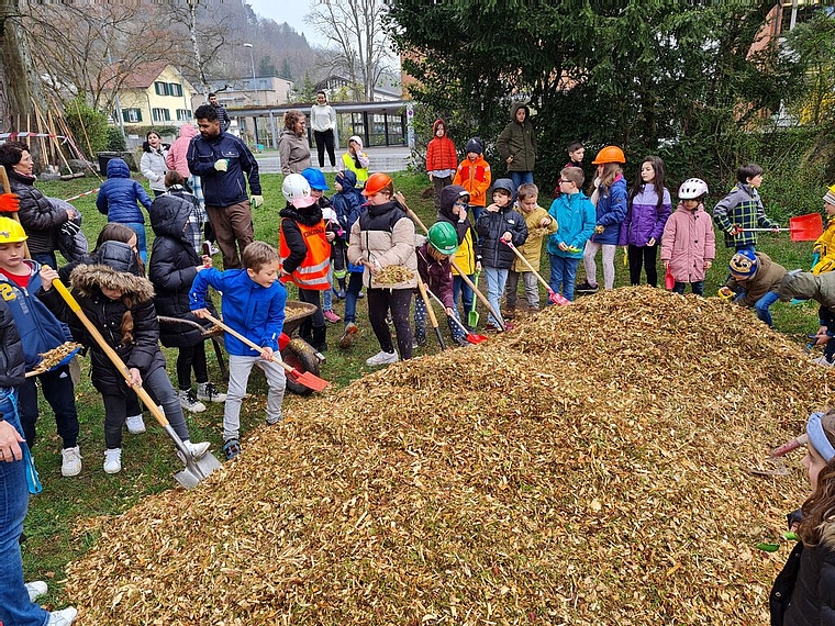 Die Primarschüler laden Holzschnitzel auf die Schaufeln. Schon im Mai sollen die Kinder auf dem neuen Spielplatz spielen können.