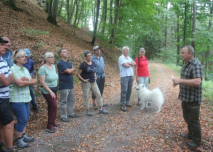 Gespannt <em>hören die Besucher den Ausführungen des Försters zu.</em>
