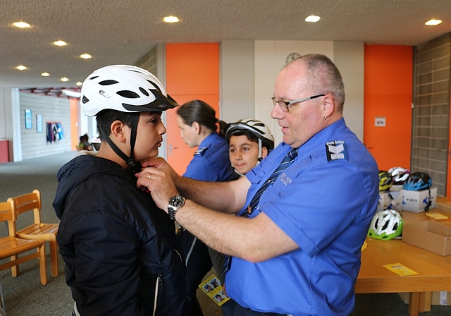 Polizist Alain Späni prüft, ob der Helm des Schülers richtig sitzt. Fotos: bär