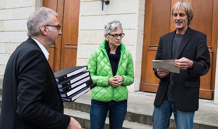 Martin Christen (r.) überreicht dem stellvertretenden Staatsschreiber Urs Meier in Anwesenheit von Grossrätin Maya Pfrunder die Unterschriften. Foto: az / jr