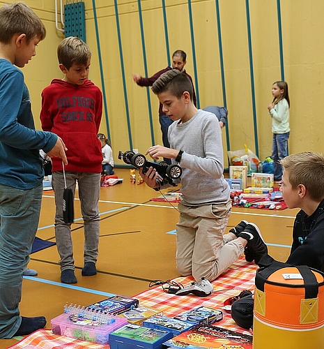 Manuel (M.) zeigt interessierten Buben, wie das ferngesteuerte Auto funktioniert, das er an seinem Stand verkauft. Melanie Bär
