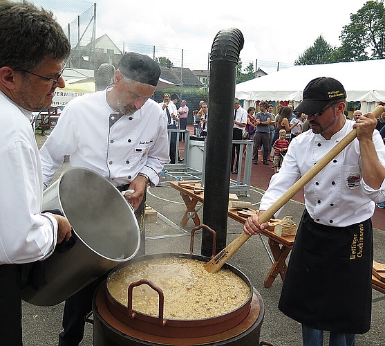 Die Wettinger Chuchimanne bereiten über dem Holzfeuer das Risotto zu, wofür die Festbesucher Schlange stehen.