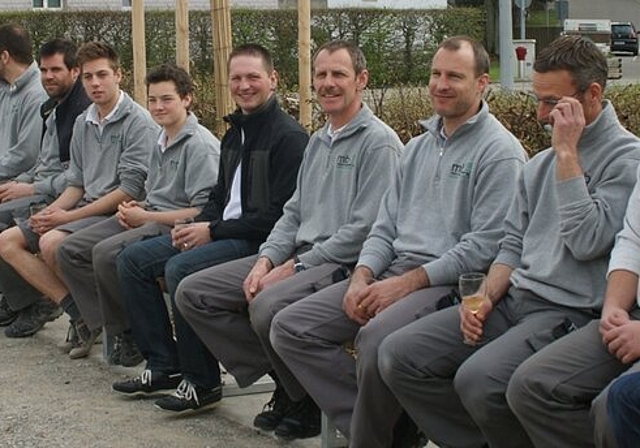Die Belegschaft der Holzwerkstatt auf der von ihr hergestellten Bank. Foto: zVg