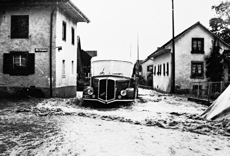 Bus auf der überschwemmten Dorfstrasse. Am Mittwoch, 13. Juli 1955, ging über Wettingen das Gewitter des Jahrhunderts nieder. Ernst Gysi, Küttigen