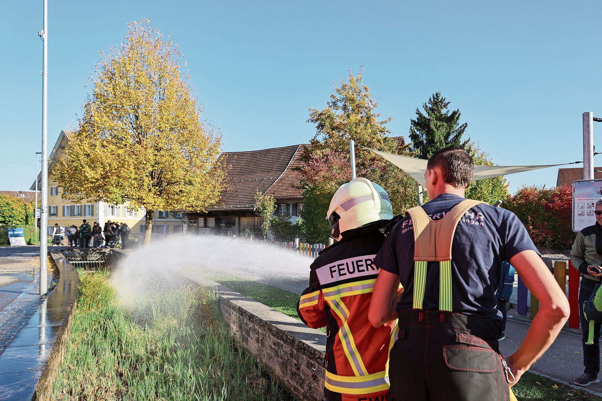 Eine Zuschauerin spritzt mit dem Wasserschlauch. gk