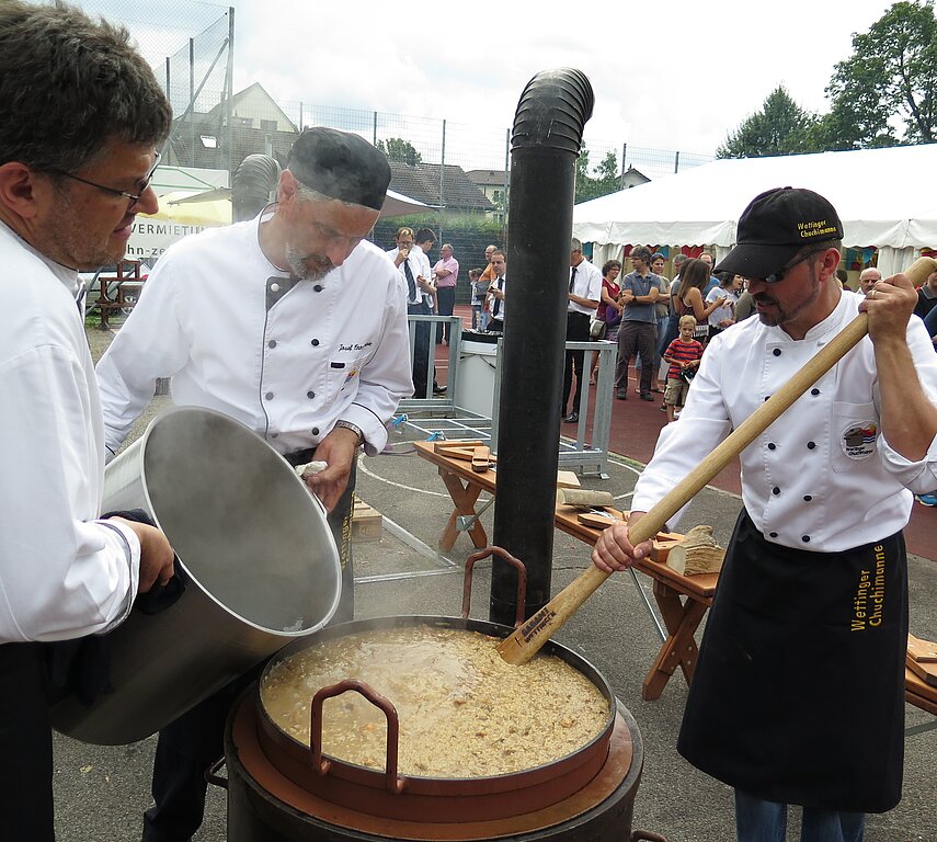 Die Wettinger Chuchimanne bereiten über dem Holzfeuer das Risotto zu, wofür die Festbesucher Schlange stehen.
