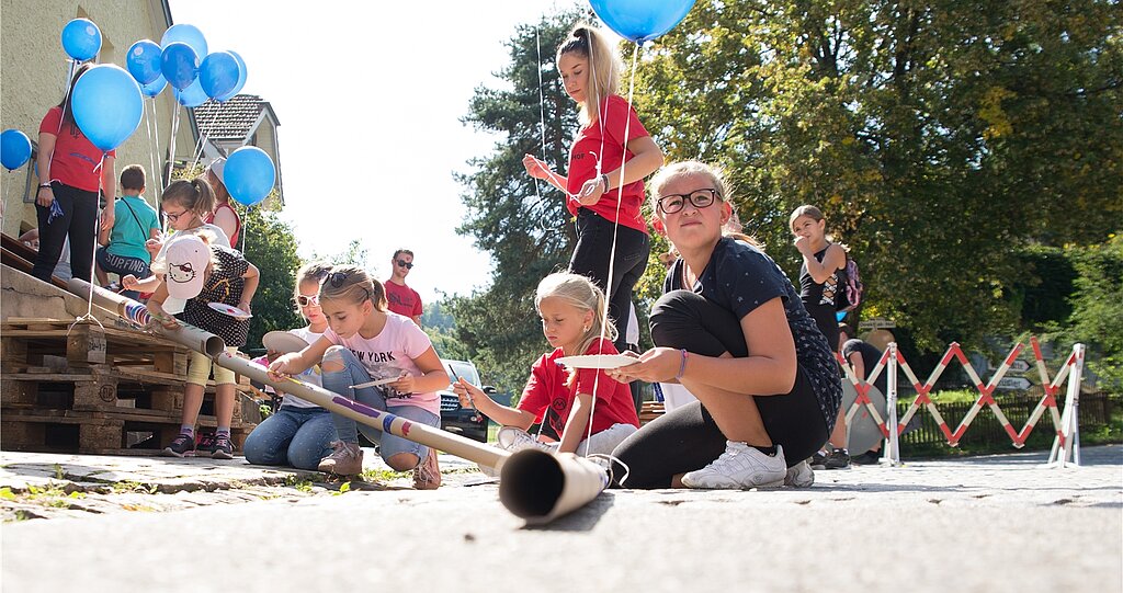 Kinder <em>bauen unter der Leitung der Jubla eine lange, bunte «Chugelibahn». </em>
