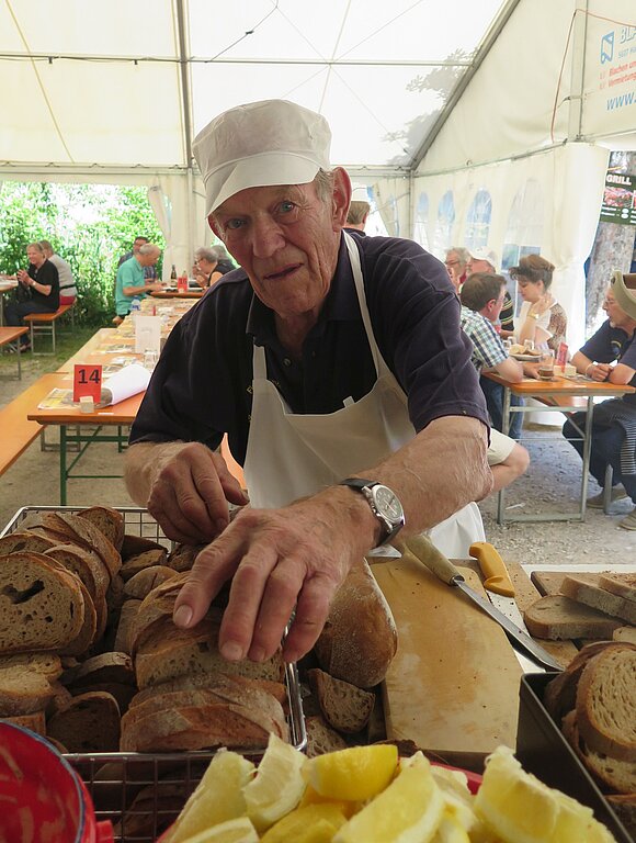 Das älteste Vereinsmitglied, Jakob Schmidt beim Brotschneiden.
