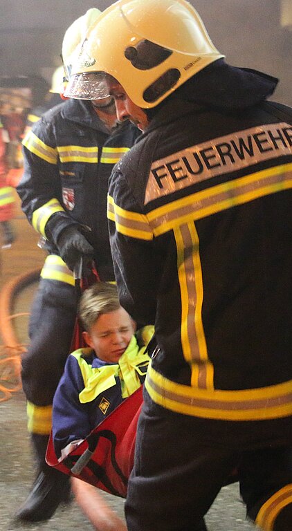 Die Feuerwehrmänner trugen einen Figuranten aus dem Haus.